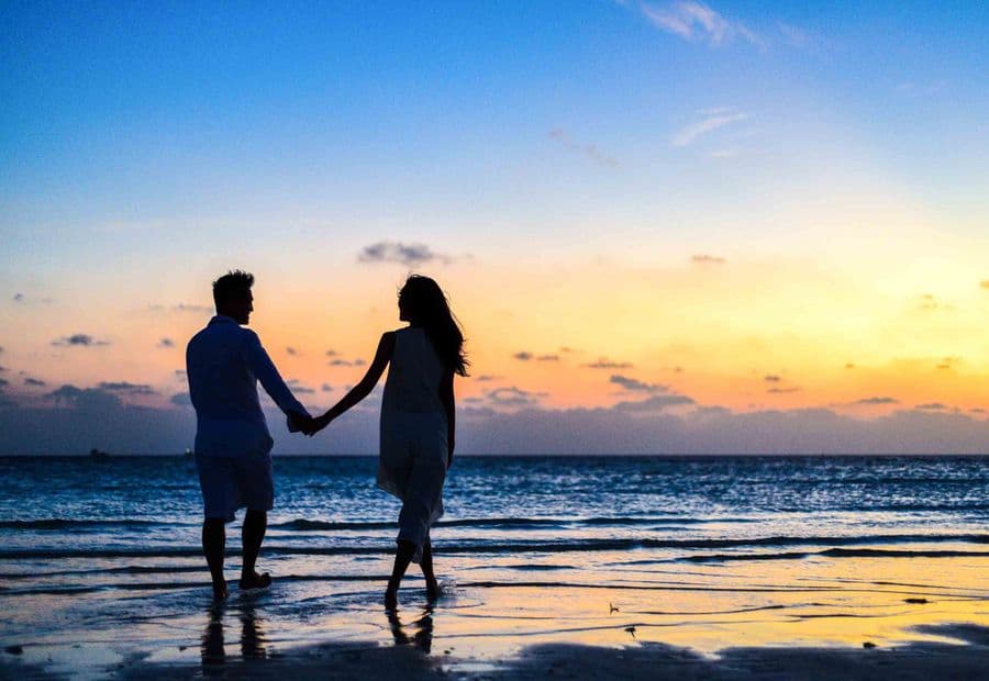 A couple holding hands at sunset by the shore