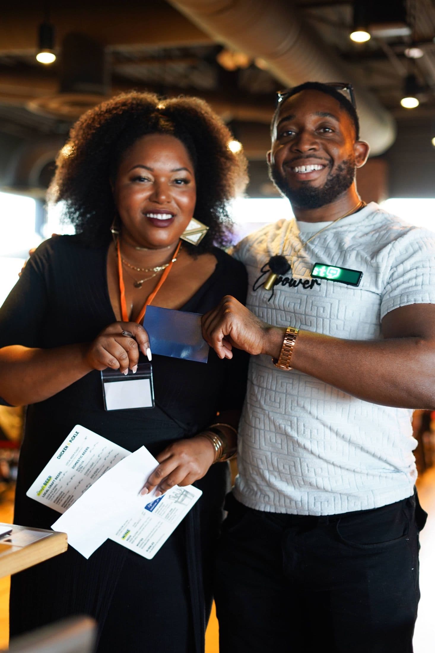 A smiling man and woman holding name badges and match cards at a Beyond The Sparks singles event.