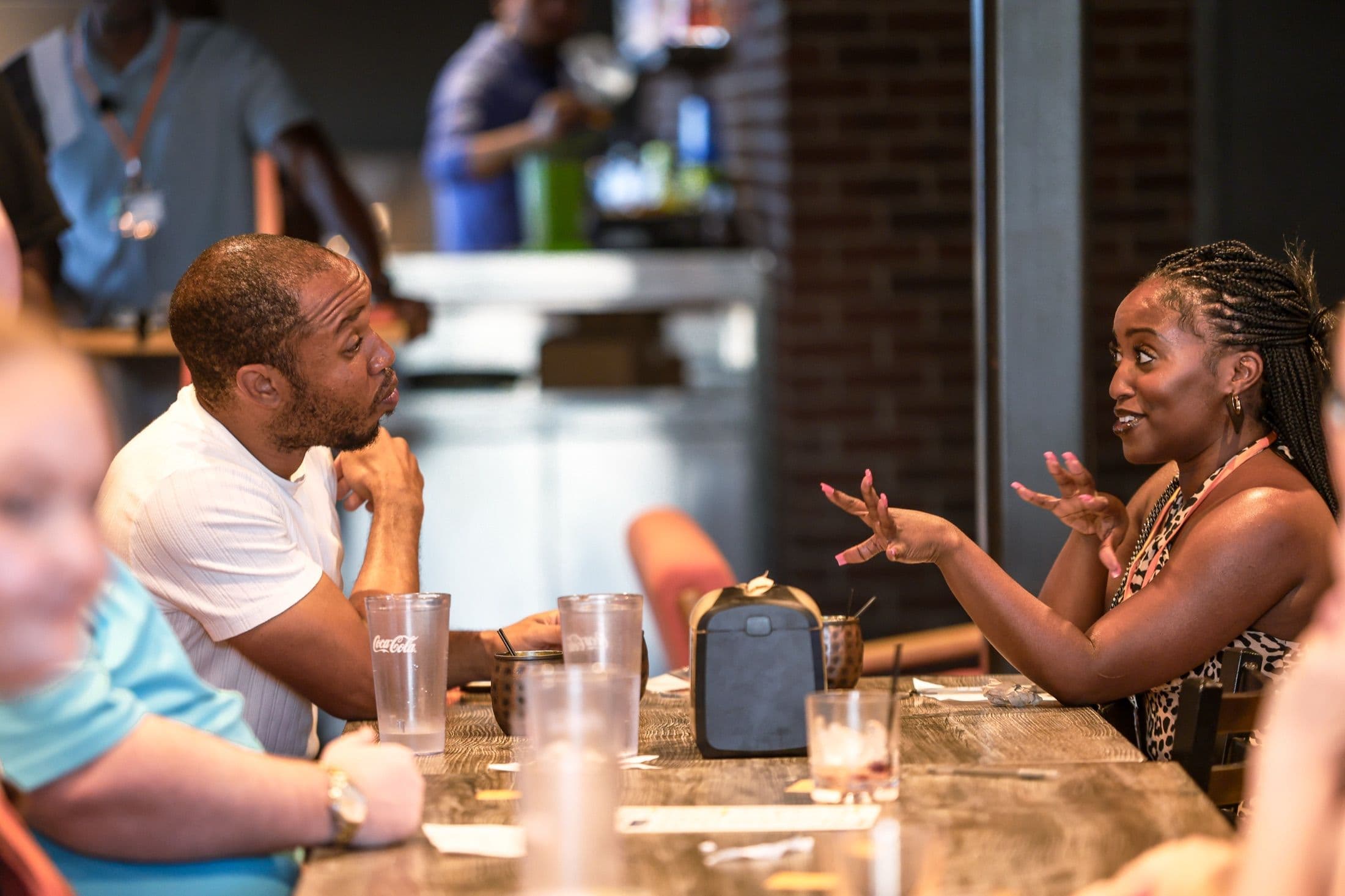 A man and woman in one-on-one conversation across a table at a Beyond The Sparks dating event.