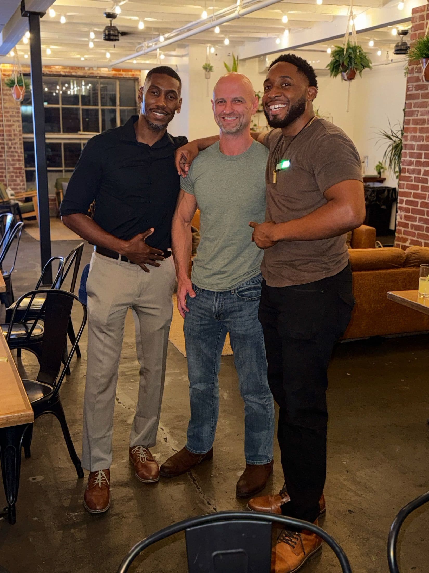 Three guests smiling arm-in-arm in the lounge at a Beyond The Sparks singles event.