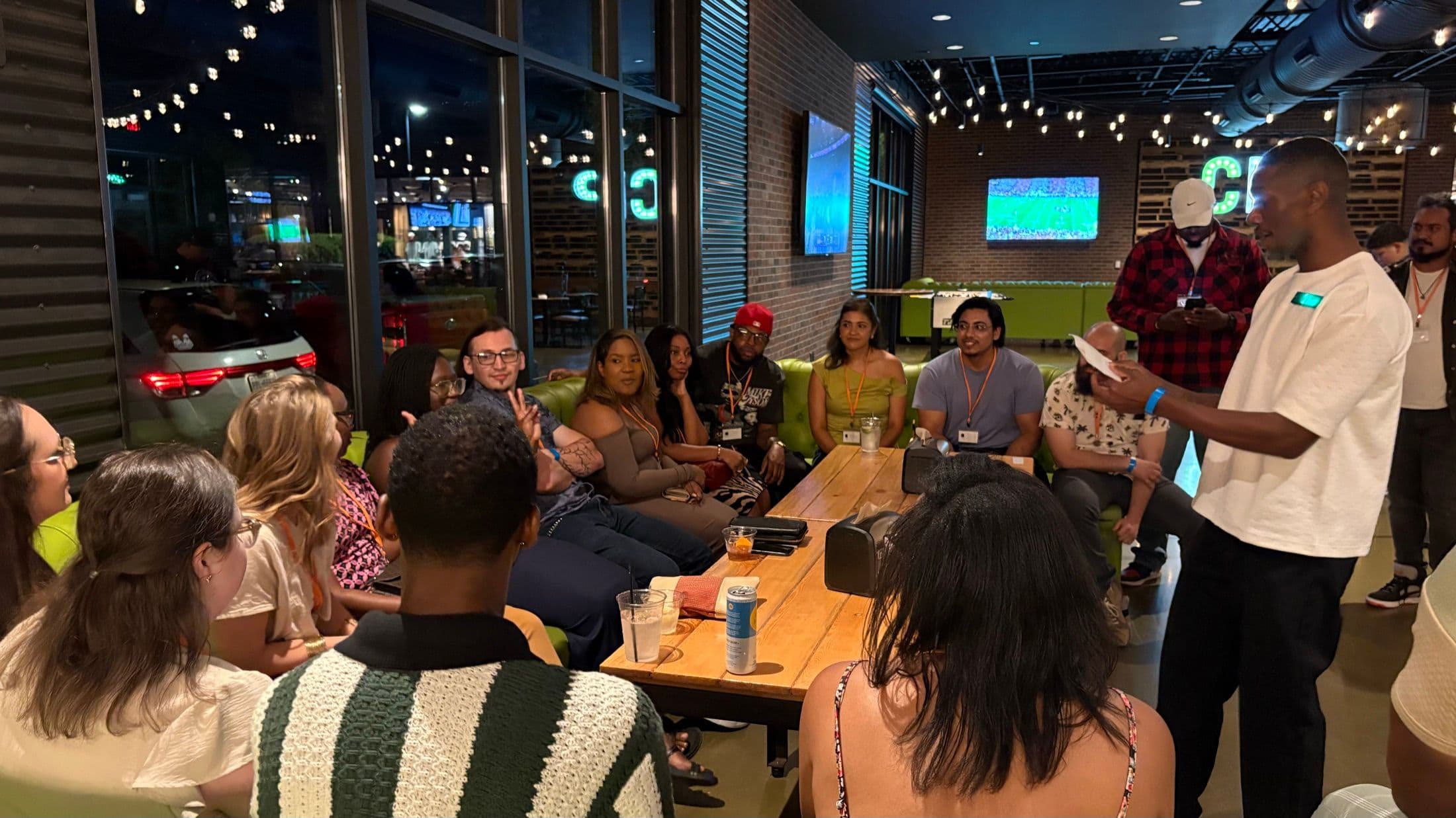 A host introducing the evening to guests seated on lounge couches at a Beyond The Sparks event.