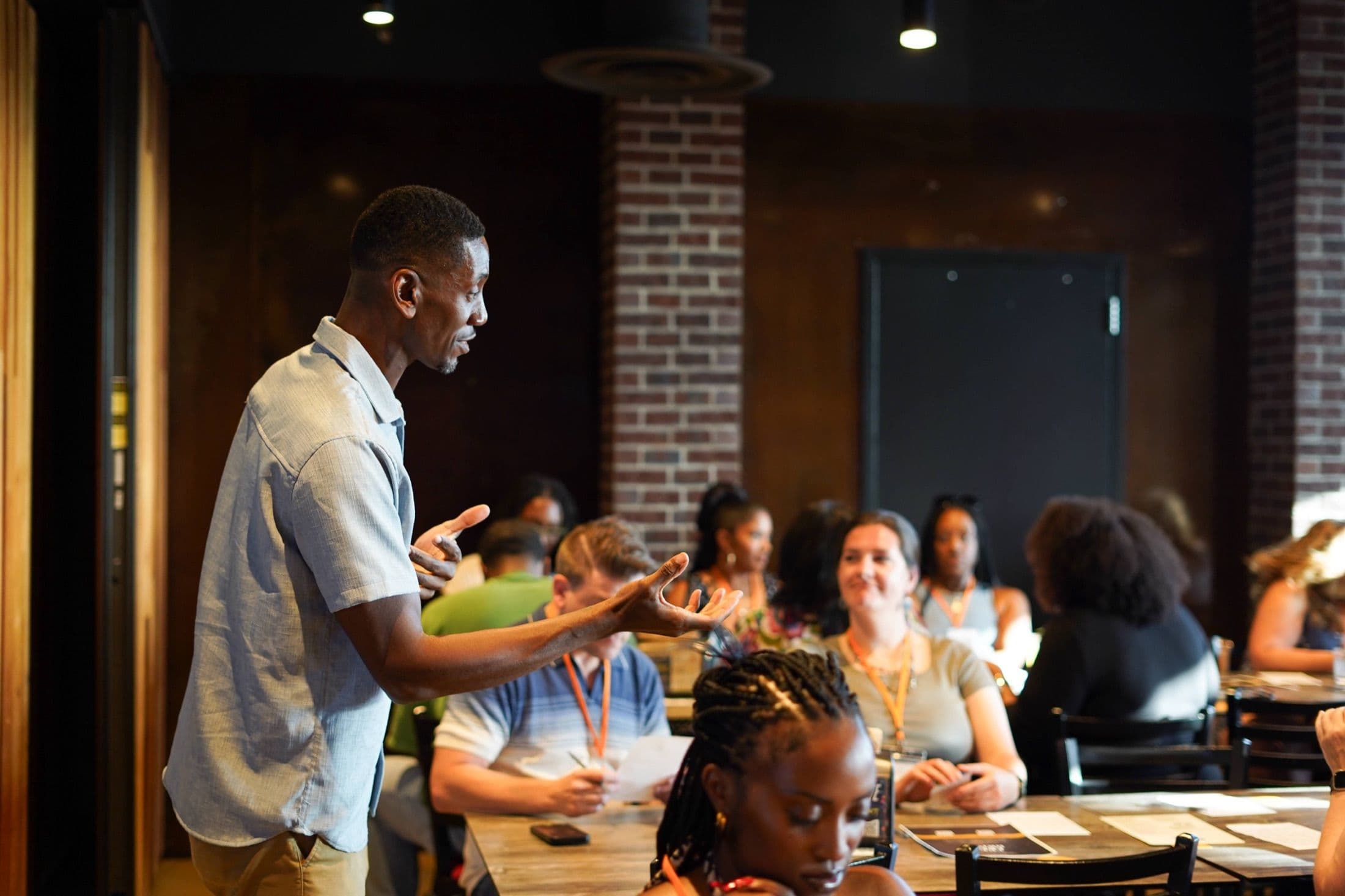 A Beyond The Sparks host speaking to seated guests at a compatibility dating event in a brick-walled venue.