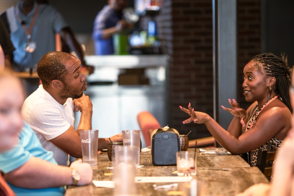 A man and woman in one-on-one conversation across a table at a Beyond The Sparks dating event.