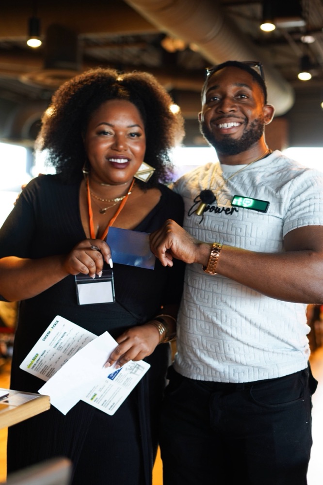 A smiling man and woman holding name badges and match cards at a Beyond The Sparks singles event.